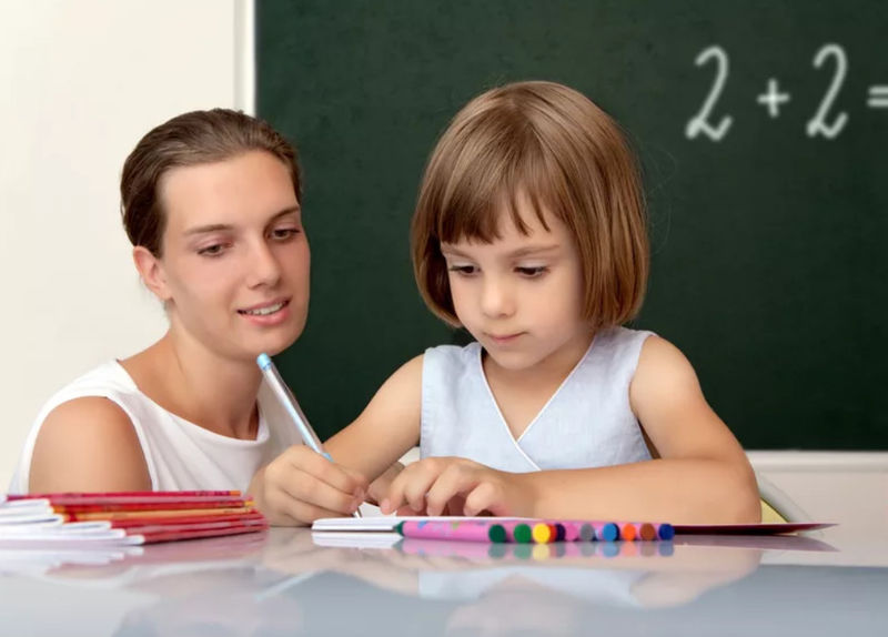 Девочка занимается математикой с учителем